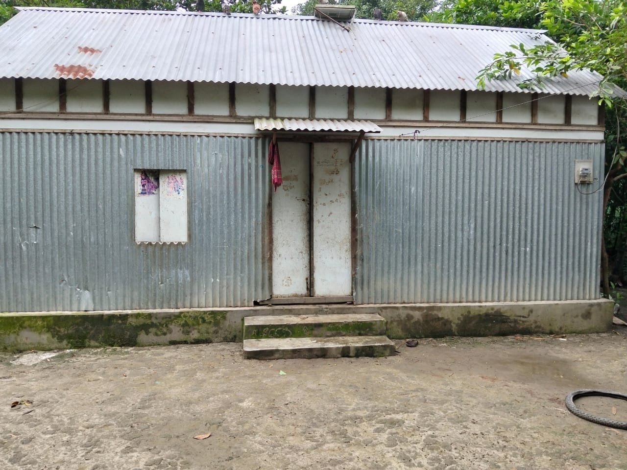 Corrugated tin house with a small awning over the door and a cloth hanging beside it.